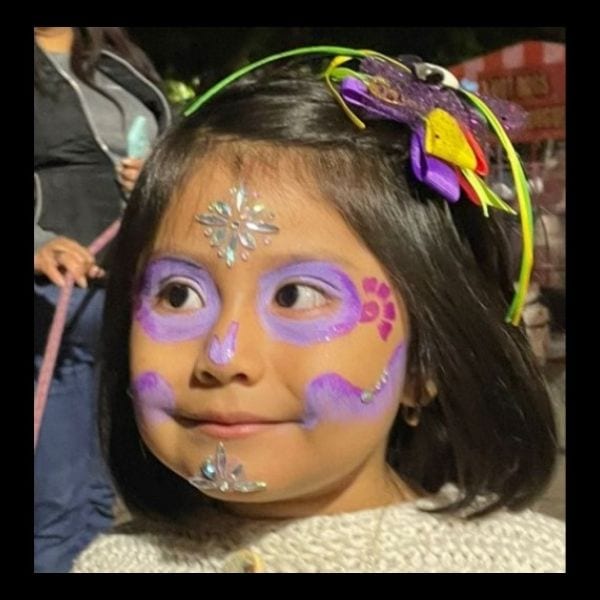 Girl with simple lilac Catrina makeup, a gem on her forehead and a flower headband